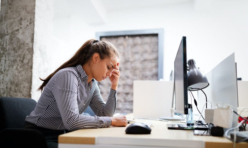 Overworked and frustrated young woman in front of computer in office